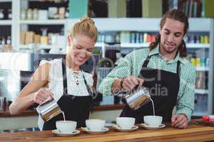 Smiling waiter and waitress making cup of coffee at counter