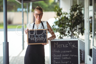 Portrait of waitress standing with chalkboard and menu
