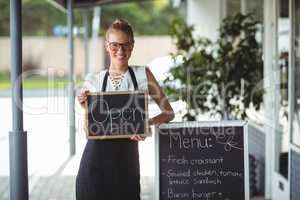 Portrait of waitress standing with chalkboard and menu