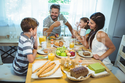 Happy family talking to each other while having breakfast together