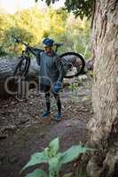 Male mountain biker carrying bicycle in the forest