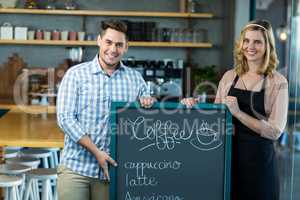 Waitress and man standing with menu board in cafe