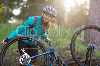 Portrait of female biker repairing mountain bike