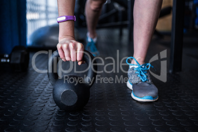 Low section of female athlete holding kettlebell in gym