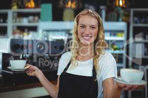 Portrait of smiling waitress offering cup of coffee