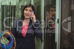 Technician holding patch cable while talking on mobile phone