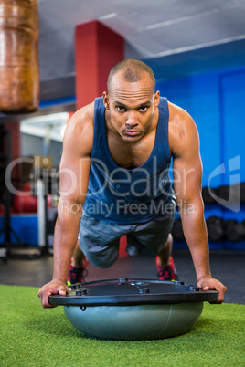 Serious young athlete with BOSU ball in gym