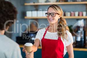 Waitress serving a coffee to customer at counter in cafÃ?Â©
