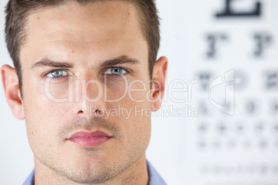 Man wearing contact lens with eye chart in background