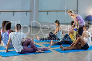 Yoga instructor helping student with a correct pose