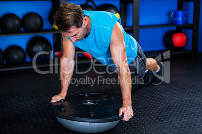 Young man with BOSU ball in gym