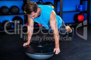 Young man with BOSU ball in gym