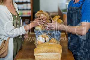 Mid section of woman purchasing bread at bakery store