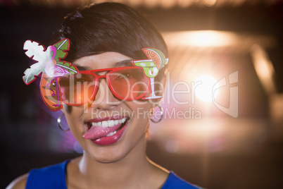 Woman wearing fancy sunglasses making funny faces in bar