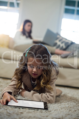 Girl using digital tablet while lying on the floor
