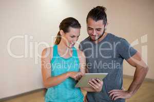 Woman showing digital tablet to fitness trainer