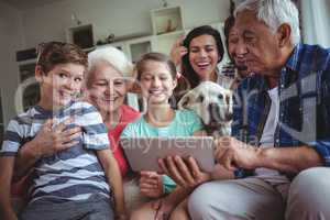 Happy multi-generation family using digital tablet in living room