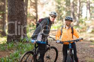 Biker couple standing with mountain bike on dirt track