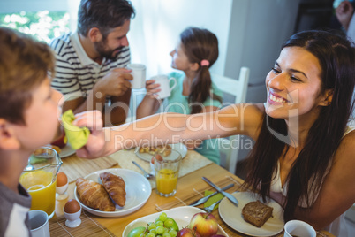 Happy woman feeding breakfast to his son