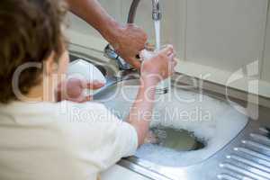 Son helping father in washing utensils