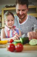 Father and daughter chopping vegetables in kitchen