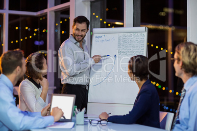 Businessman discussing graph on whiteboard with colleagues