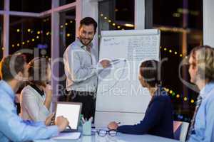 Businessman discussing graph on whiteboard with colleagues