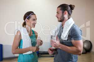 Fitness trainer and woman holding water bottle
