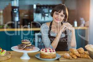 Portrait of waitress sitting at counter with sweet food on table
