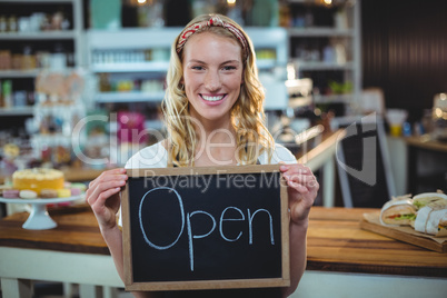 Smiling waitress showing chalkboard with open sign