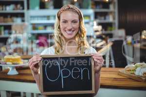 Smiling waitress showing chalkboard with open sign