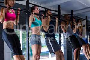 Young friends doing chin-ups in gym