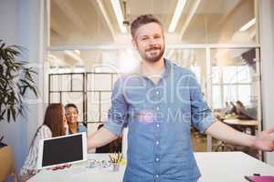 Smiling businessman with arms outstretched against coworkers