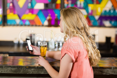 Beautiful woman using mobile phone while having beer