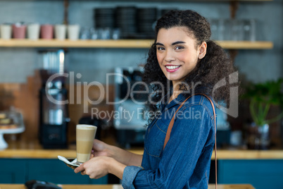 Smiling woman holding a cup of coffee in cafÃ?Â©