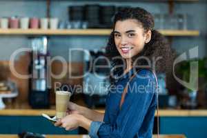 Smiling woman holding a cup of coffee in cafÃ?Â©