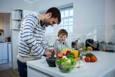 Boy looking while father chopping vegetables