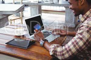 Man doing online shopping with credit card on laptop