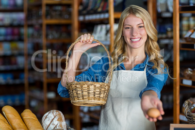 Smiling female staff holding basket and egg in super market