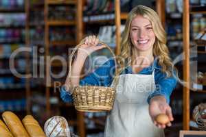 Smiling female staff holding basket and egg in super market