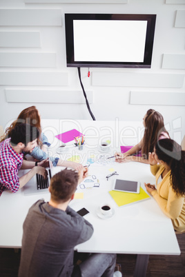 High angle view of business people watching at television in creative office