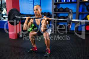 Male athlete weightlifting in fitness studio