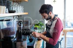 Waiter making cup of coffee in cafe