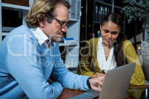 Business executives discussing over laptop