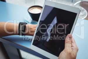 Businesswoman using digital tablet while having coffee