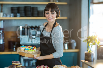 Portrait of waitress holding cup cake on tray in cafÃ?Â©