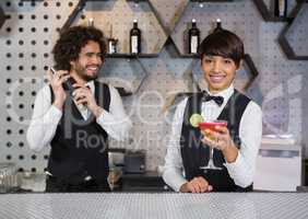 Two bartenders preparing cocktail and serving in bar counter