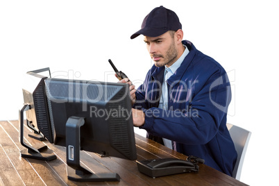 Security officer looking at computer monitors and talking on walkie-talkie