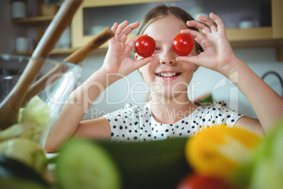 Playful girl holding cherry tomato on her eye