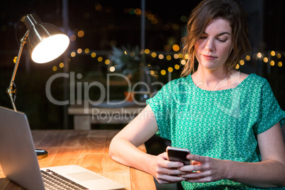 Businesswoman using mobile phone at her desk